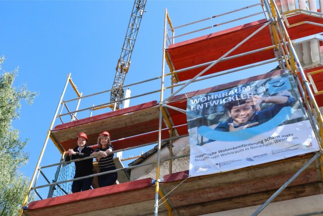 Nils Kater und Wiltrud Grünebaum stehen auf dem Baugerüst der aufgestockten Gebäude.