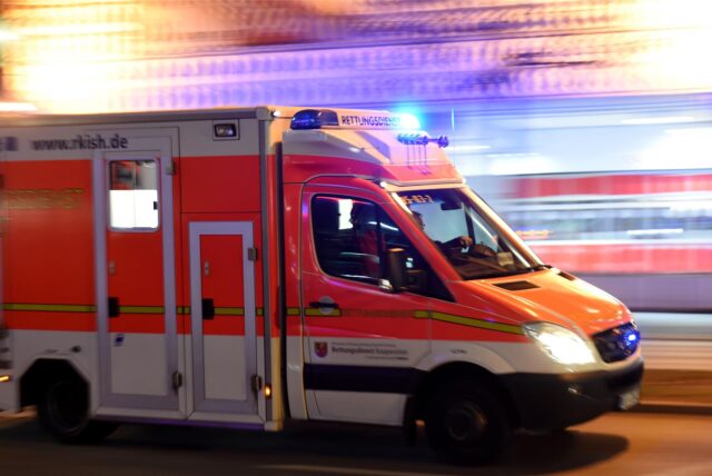 Ein Krankenwagen mit Martinshorn fährt eine Straße entlang.