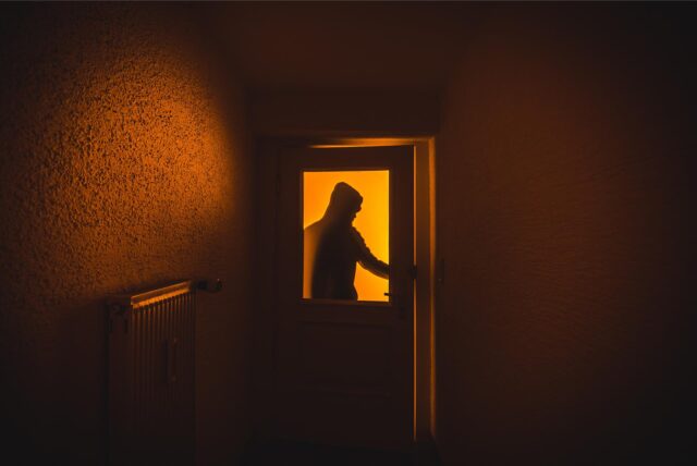 Ein Einbrecher öffnet eine Wohnungstür.