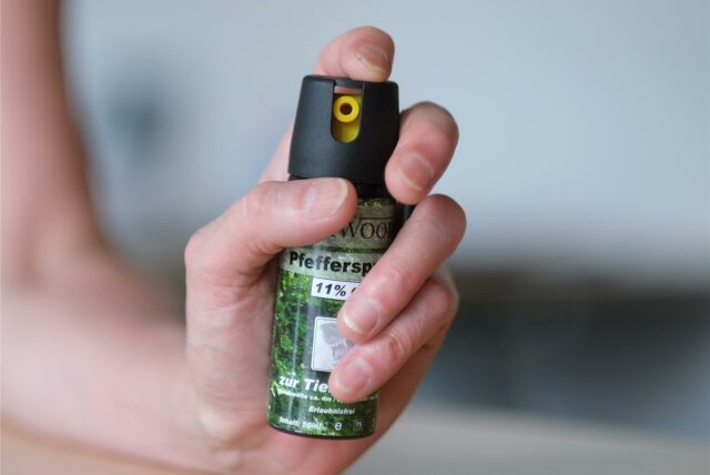 Eine Person hält eine Pfefferspraysprühdose in die Kamera.