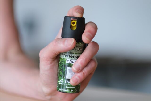 Eine Hand hält eine Kartusche mit Pfefferspray.