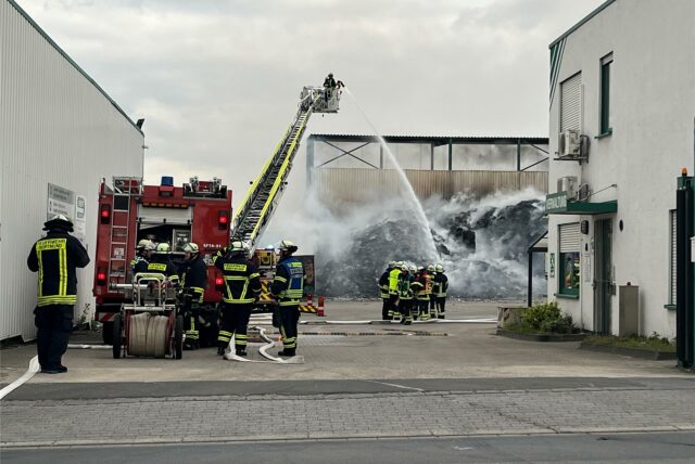 Einsatzkräfte der Feuerwehr löschen einen brennenden Haufen Material bei einem Recyclingunternehmen in Dortmund