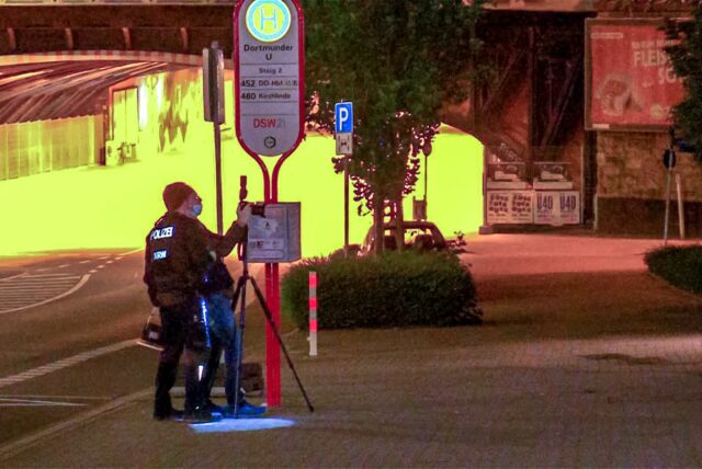 Ermittler der Polizei fotografieren einen mutmaßlichen Tatort nahe einer Bushaltestelle
