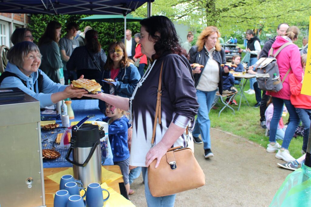 Eine Besucherin des Frühlingsfestes auf dem Hof Wessels in Herten bekommt an einem Stand eine Waffel in die Hand.