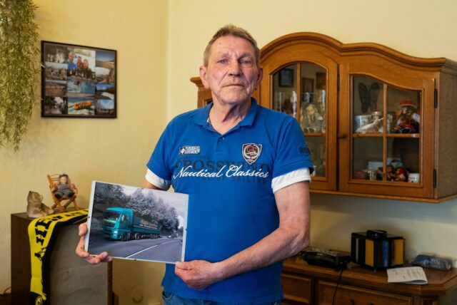 Manfred Pohl in seinem Wohnzimmer hält ein Bild eines Lkw
