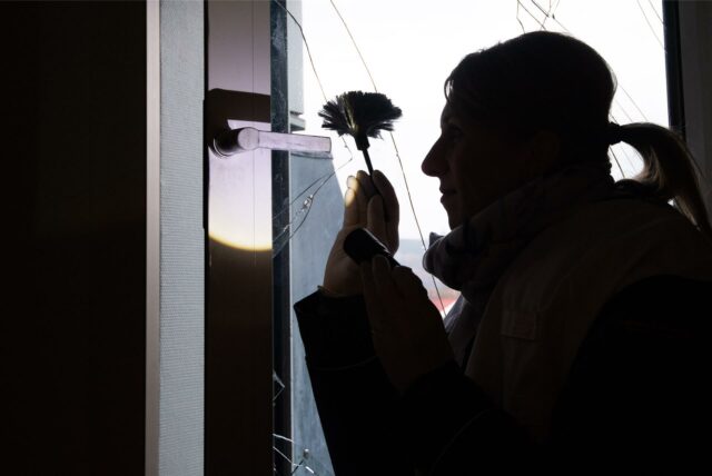 Eine Polizistin sichert Spuren an einem beschädigten Fenster.