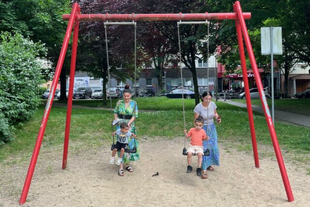 Kinder schaukeln auf dem Spielplatz Leibnizstraße.