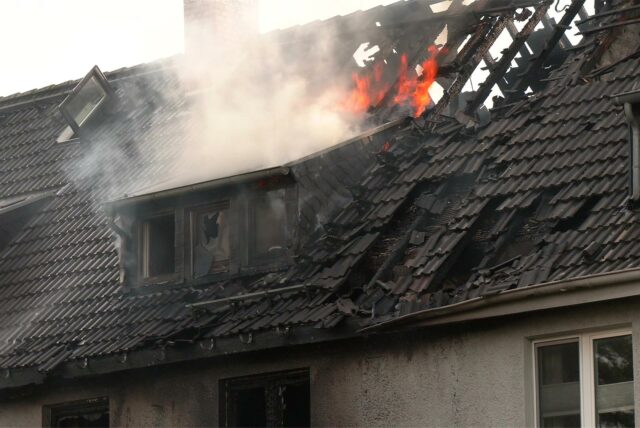 Flammen und Rauch schlagen aus dem Dachstuhl eines abgebrannten Reihenhauses.