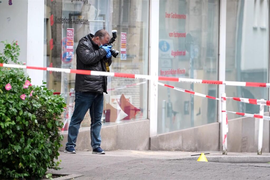 Eine Einsatzkraft fotografiert den Tatort. Nach Schüssen in der Essener Innenstadt fahndet die Polizei mit einem Großaufgebot nach den geflohenen Tätern. 
