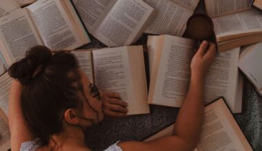 Frau liegt auf vielen offenen Bücher und hat einen Kaffe in der Hand.