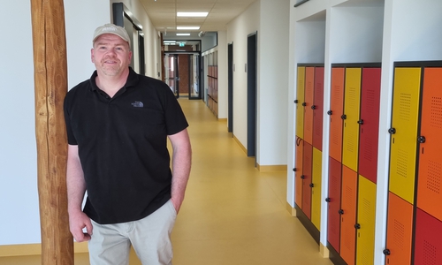 Arne Rosenhagen auf dem Flur des Erweiterungsgebäude, das Farbkonzept von außen wird im Gebäudeinnern fortgesetzt. 