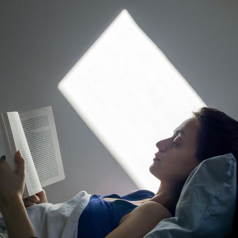 Eine Frau liegt im Bett und liest ein Buch.