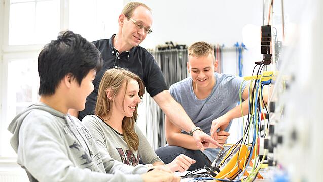 Gruppe junger Auszubildender und Ausbilder in einem Elektrobetrieb.