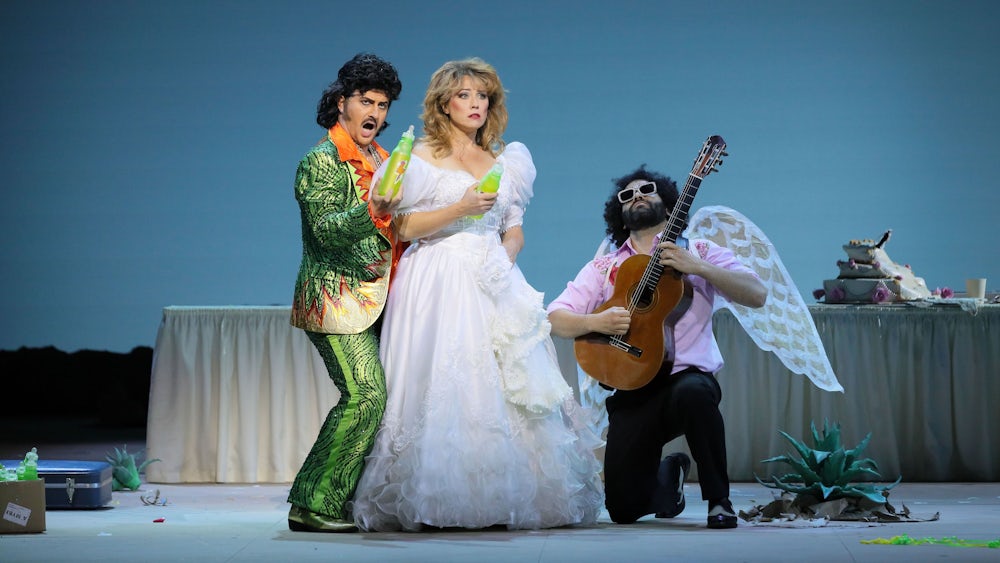 Levente Páll (li.) sieht als Dulcamara aus wie Elvis mit Schnauzbart, Jennifer O’Loughlin als Adina teils nach Disco-Ära. Begleitet werden sie in den Rezitativen vom Gitarren-Amor Pedro Aguiar.