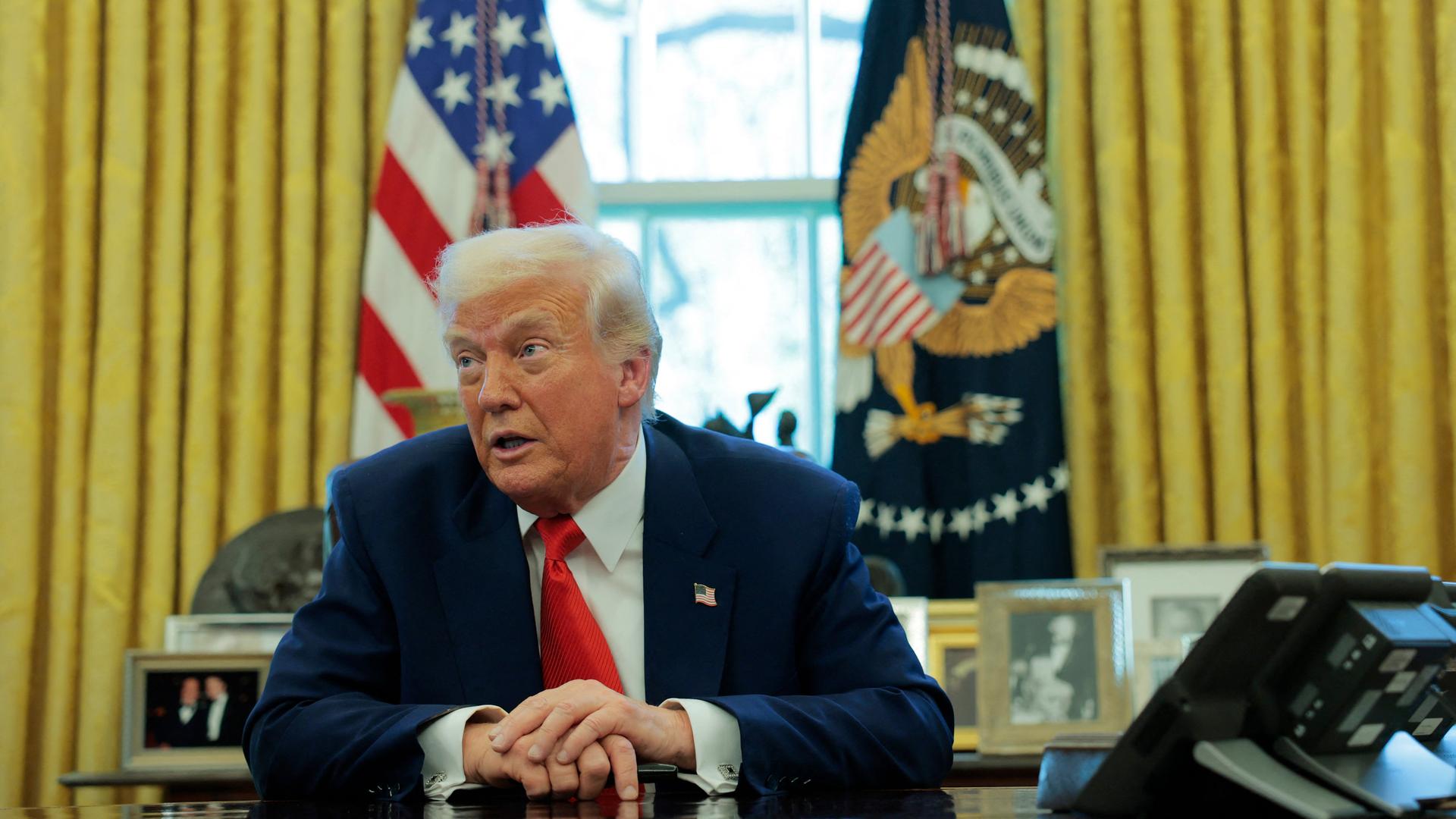 US-Präsident Donald Trump sitzt an seinem Schreibtisch und spricht.