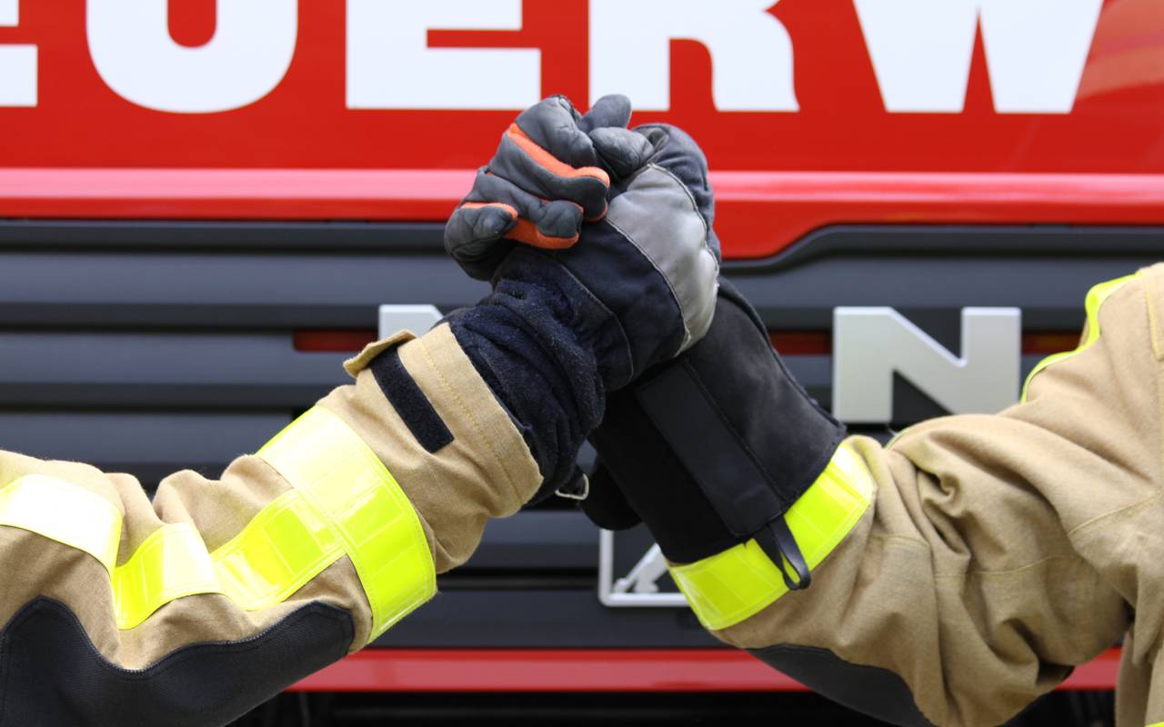 Zwei Feuerwehrleute machen einen Handshake. 