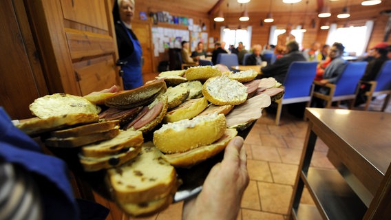 Eine Mitarbeiterin trägt ein volles Tablett mit belegten Brötchen. © pictue alliance Foto: Angelika Warmuth