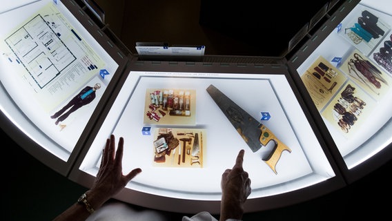 Eine Frau zeigt auf eine "Fuchsschwanz" Säge, das mutmaßliche Tatwerkzeug des Mörders Fritz Honka, in einer Vitrine im Polizeimuseum. © Picture Alliance/dpa Foto: Christian Charisius