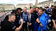 Hamburgs Erster Bürgermeister Peter Tschentscher (M.) steht während der Aufstiegsfeier inmitten der HSV-Spieler auf dem Balkon vom Hamburger Rathaus. © Witters/TimGroothuis 