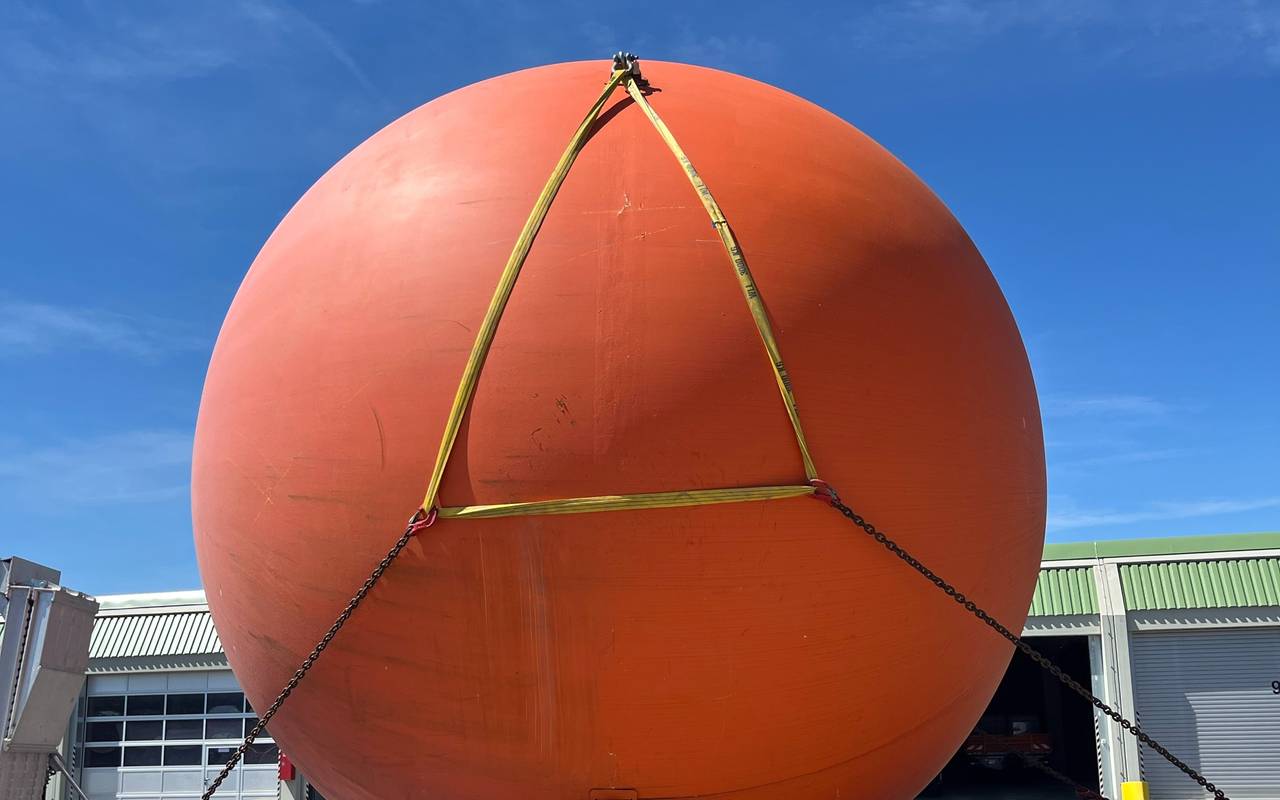 Eine riesige orangefarbene Kugel auf einem LKW-Anhänger.