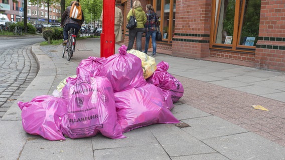 Rosa Müllbeutel der Stadtreinigung liegen befüllt an einer Straßenlaterne. © picture alliance Foto: Alexander Bernhard