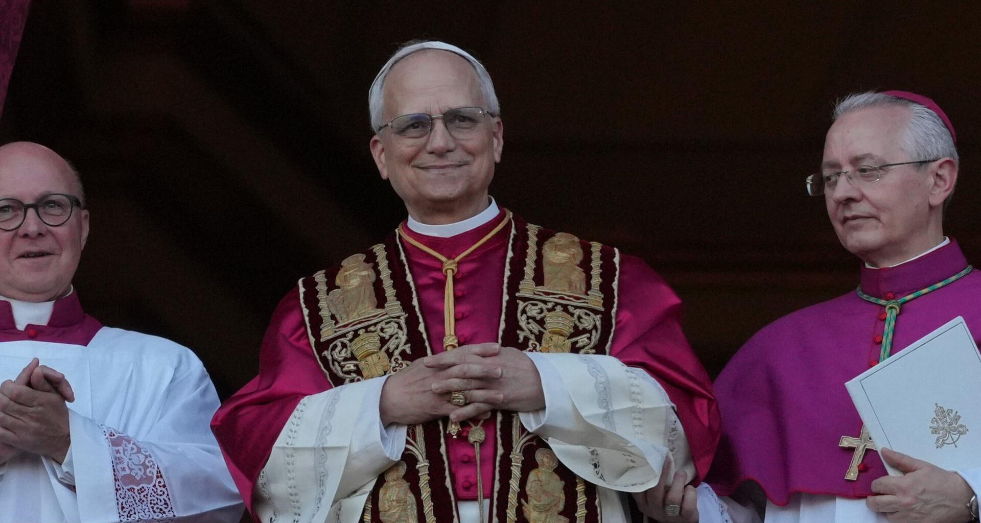 Der neu gewählte Papst, Leo XIV, steht auf dem Balkon des Petersdoms im Vatikan am 8. Mai 2025. Seine Hände sind gefaltet und er hat ein Lächeln auf den Lippen - Er scheint sichtlich glücklich über sein neues Amt.