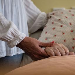 In einem Pflegeheim der Paritätischen Seniorenwohnen gGmbH hält eine Frau die Hand einer Pflegebedürftigen. (Quelle: dpa/Paul Zinken)