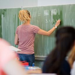 Symbolbild: Eine junge Lehrerin schreibt an eine Schultafel im Mathematikunterricht an einer Integrierten Gesamtschule am 09.06.2022. Quelle: picture alliance/dpa/Julian Stratenschulte)