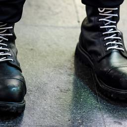 Schwarze Springerstiefel mit weißen Schnürsenkeln. 