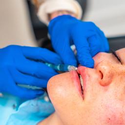 Frau, die eine Injektion zur Vergrößerung des Lippenvolumens im Rahmen einer Gesichtsverschönerungsmaßnahme in der Klinik erhält (Quelle: dpa/Unai Huizi)
