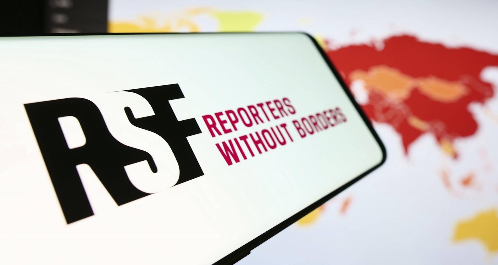 Ein Mobiltelefon mit dem Logo der internationalen Organisation Reporter ohne Grenzen vor einer Website.