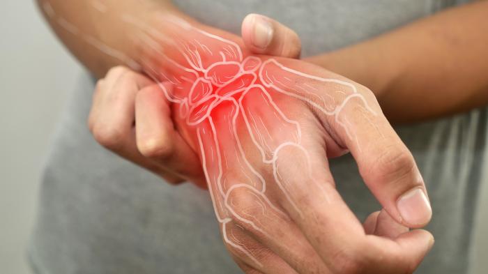 Anonyme Person, die sein Handgelenk berührt, an Arthritis erkrankt ist, Nahaufnahme auf grauem Hintergrund