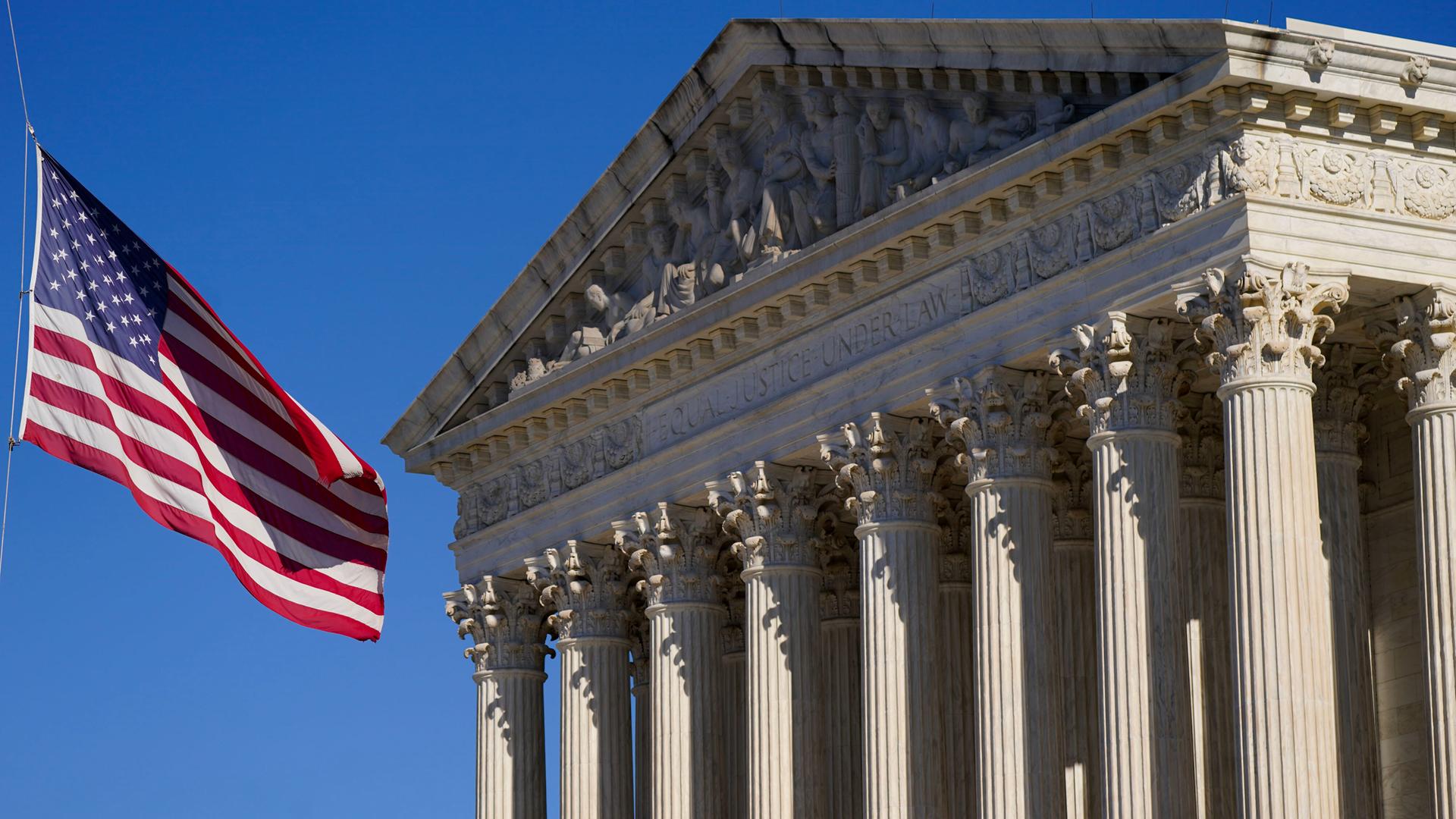 Eine US-Flagge weht im Wind vor dem Gebäude des Supreme Courts in Washington mit der Inschrift "Equal justice under law".