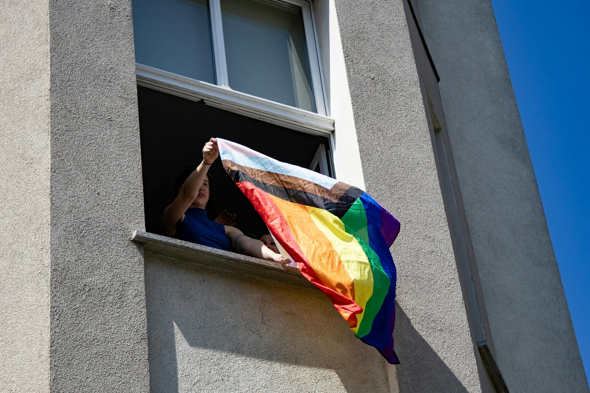 Anwohner unterstützen die Demonstrierenden, manche winken mit Pride-Flaggen aus den Fenstern.