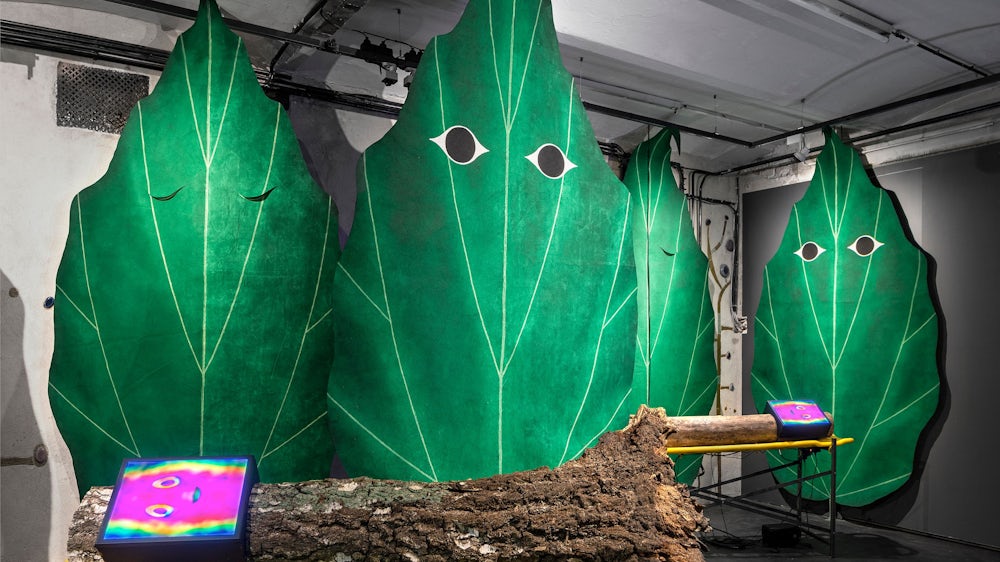Shakespeare lässt grüßen: Die Installation „The Sonnenschein Rhapsodies“ von Böhler & Orendt aus dem Jahr 2023 ist bei Nicole Gnesa zu sehen. Die Installation weist eine beachtliche Anzahl an Elementen auf: Stahl, Baumstämme, Spineboards, Flatscreen-Displays, Ein-Platinen-Rechner, LAN-Netzwerk, Lautsprecher, Kabel, Lack, Bühnenfilz, sieben Videoloops.