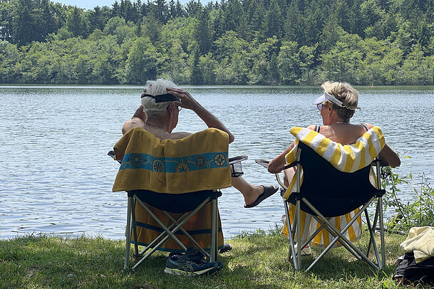 Älteres Ehepaar genießt das warme Wetter am Steinsee bei München.