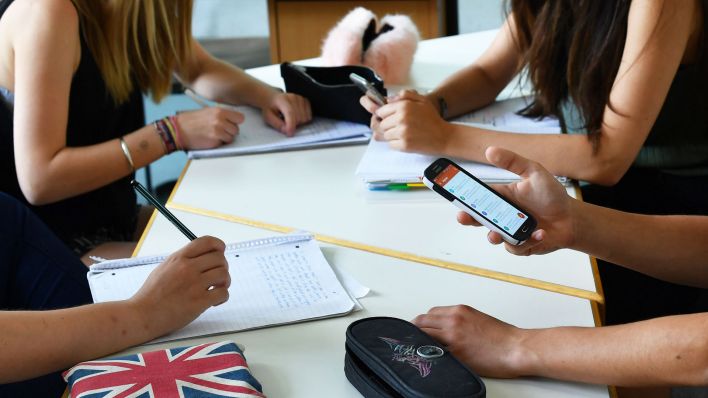 Ein Schüler hält im Unterricht ein Handy in den Händen. (Quelle: dpa/Jens Kalaene)