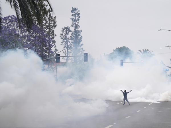 Rauch füllt die Straße, als Demonstranten während einer Demonstration im Paramount-Viertel von Los Angeles den Grenzschutzbeamten gegenüberstehen. Die Demonstranten protestieren gegen die Operation der Bundeseinwanderungsbehörde vom Vortag bei der die Behörden Dutzende von Menschen festgenommen hatten. +++ dpa-Bildfunk +++