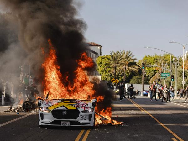 LOS ANGELES, CALIFORNIA - JUNE 8: Several cars burn on North Los Angeles street during clashes between protesters and police on June 8, 2025 in Downtown Los Angeles, California. The clashes come after ICE raids swept throughout the city over the weekend.   Jim Vondruska/Getty Images/AFP (Photo by Jim Vondruska / GETTY IMAGES NORTH AMERICA / Getty Images via AFP)