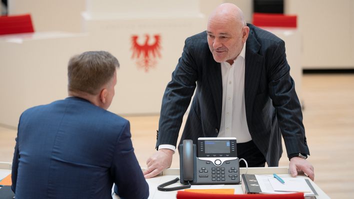 Archivbild: Robert Crumbach (r, BSW), Brandenburgs Minister der Finanzen und für Europa, und Steeven Bretz (l), Parlamentarischer Geschäftsführer der Brandenburger CDU-Fraktion, unterhalten sich am 10.04.2025 vor Beginn der Sondersitzung des Brandenburger Landtages zum Doppelhaushalt des Landes für die Jahre 2025 und 2026. (Quelle: Picture Alliance/Soeren Stache)