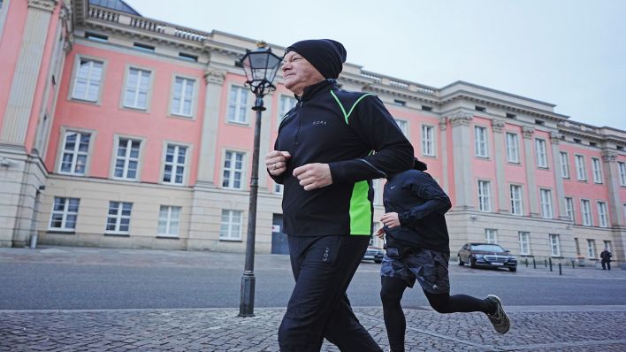 23.02.2025, Brandenburg, Potsdam: Bundeskanzler Olaf Scholz (SPD, l) joggt in Begleitung von seinem Personenschutz am Morgen.(Quelle:dpa/M.Kappeler)