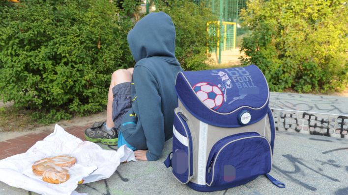 Symbolbild: Ein Junge sitzt mit seinem Schulranzen auf einer Tischtennisplatte auf einem Spielplatz in Berlin und spielt auf einem Smartphone. (Quelle: dpa/Kalaene)