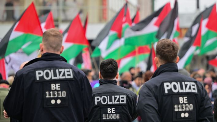 Archivbild: Palästinensische Fahnen werden während einer propalästinensischen Demonstration hinter Polizeibeamten geschwungen. (Quelle: dpa/Gollnow)