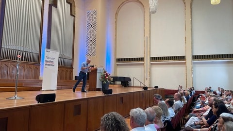 Harald Lesch gestikuliert auf der Bühne des Festsaals der Uni Tübingen. Die Mediendozentur ist eine gemeinsame Veranstaltung der Uni und des SWR Studios Tübingen. 