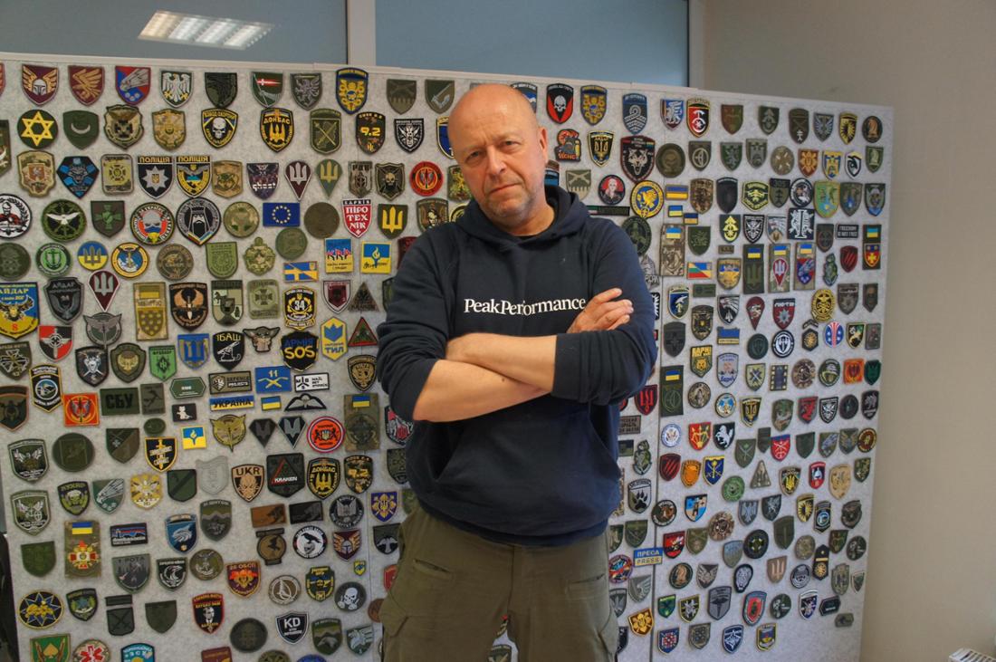 blue-yellow-Gründer Jonas Öhman vor einer Stellwand mit ukrainischen Militärabzeichen