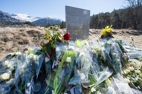 Inmitten von Blumen steht eine steinerne Gedenkstele mit der Aufschrift "In Erinnerung an die Opfer des Flugzeugunglücks vom 24. März 2015" in den vier Sprachen Englisch, Deutsch, Spanisch und Französisch. - © picture alliance / dpa