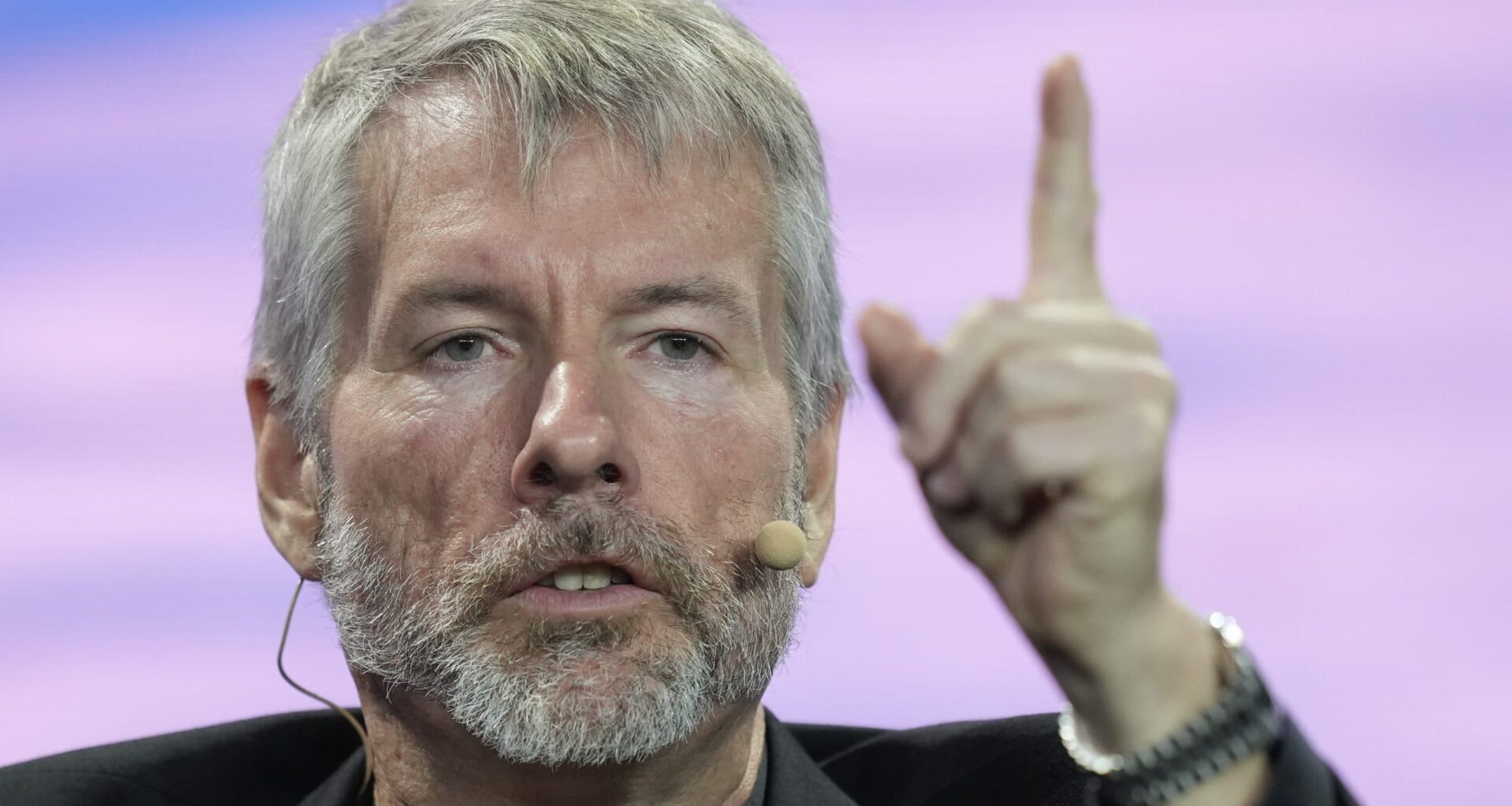 Michael Saylor gestikuliert mit einem erhobenen Finger, als würde er die Feinheiten von Bitcoin erklären, und zugleich vor XRP und Ripple warnen