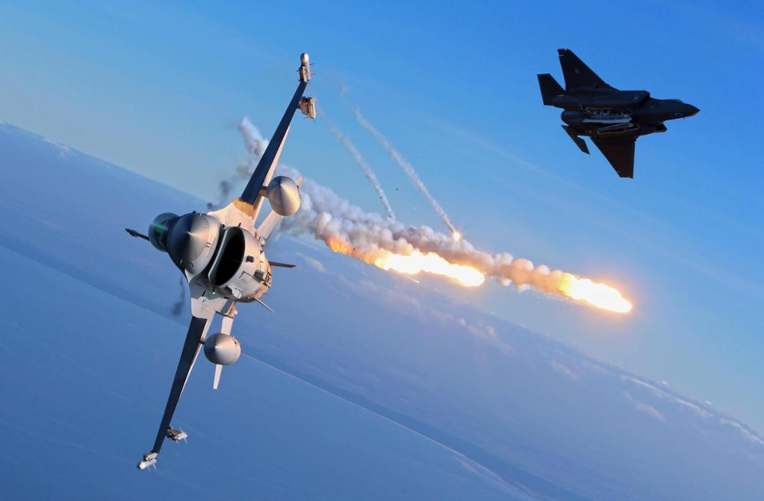 Die F-16 feuert IR-Teuschkörper (Flares) ab. Kampfflugzeuge vom Typ Lockheed Martin F-35A Lighting II (oben rechts) und eine Lockheed Martin F-16 Fighting Falcon (vorne) bei einer Übung. 