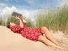 Eine Frau liest ein Buch in einer Düne am Strand (Symbolfoto)