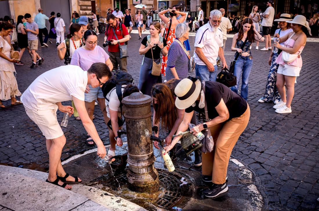 Touristinnen und Touristen suchen an einem Trinkbrunnen Abkühlung. In Italien herrschen besonders hohe Temperaturen. 